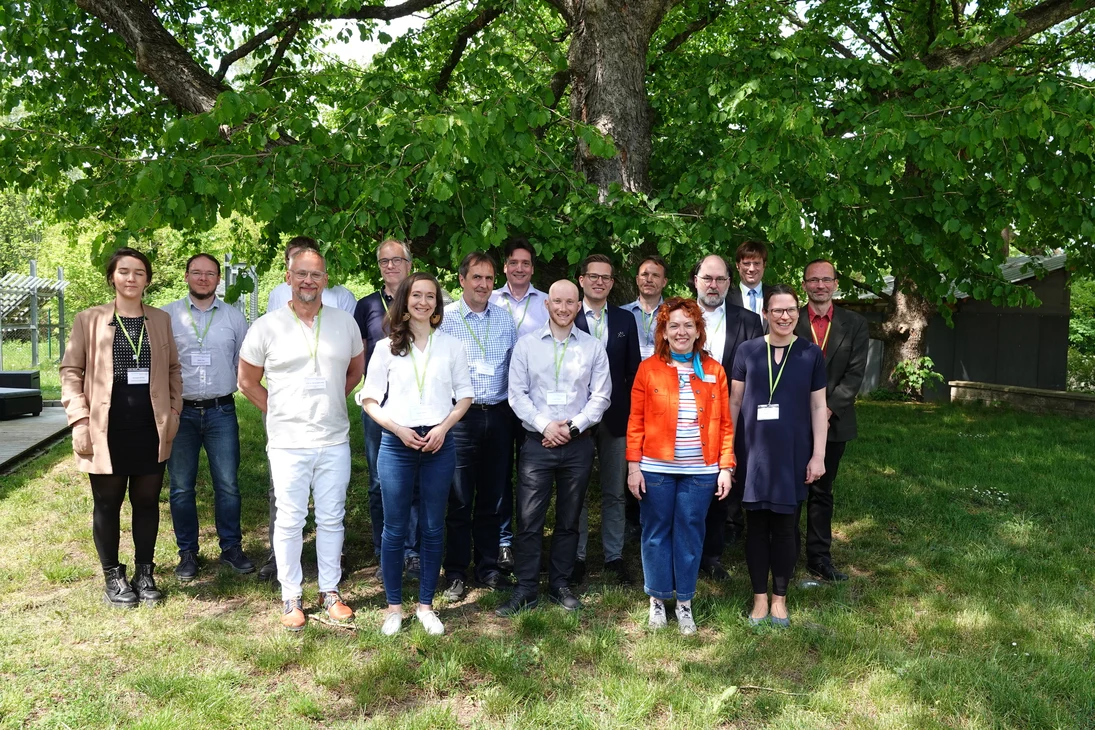Mehrere Personen stehen für ein Gruppenfoto vor einem Baum.