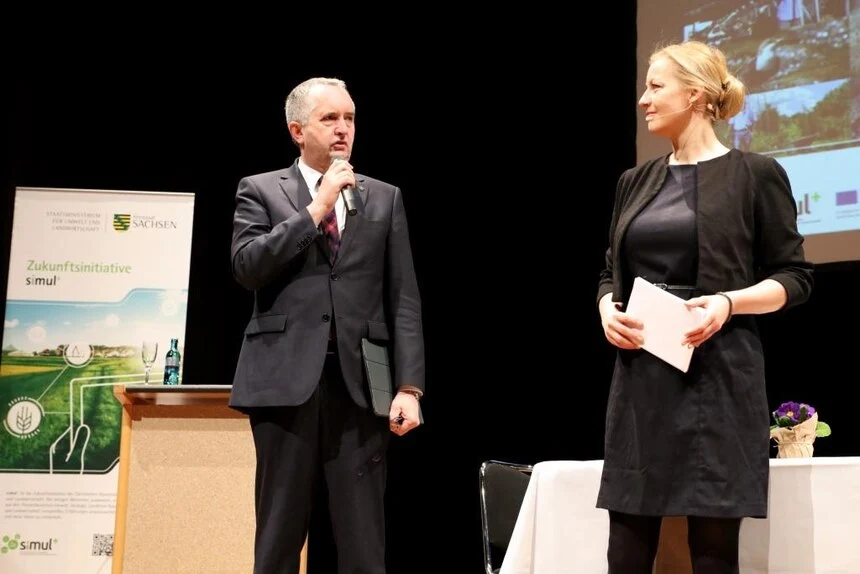 Staatsminister Schmidt im Bühnengespräch mit einer Frau.