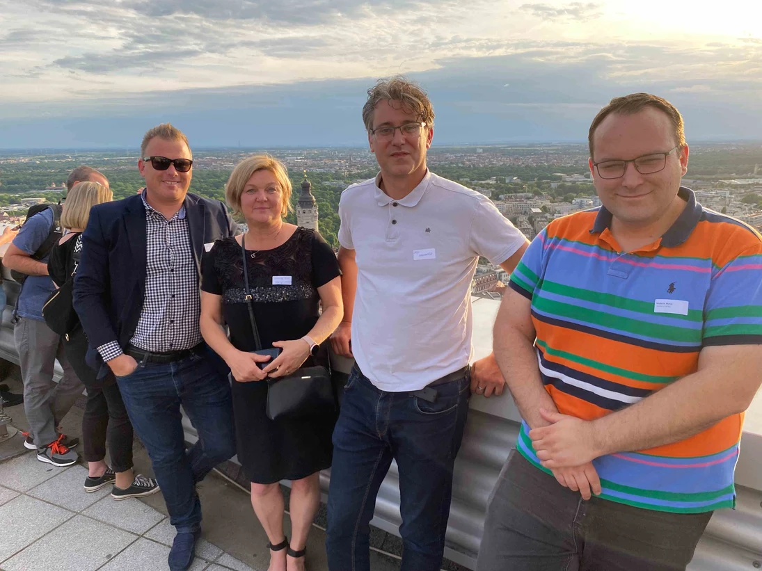 Personen stehen auf einer Dachterrasse mit Blick über Leipzig