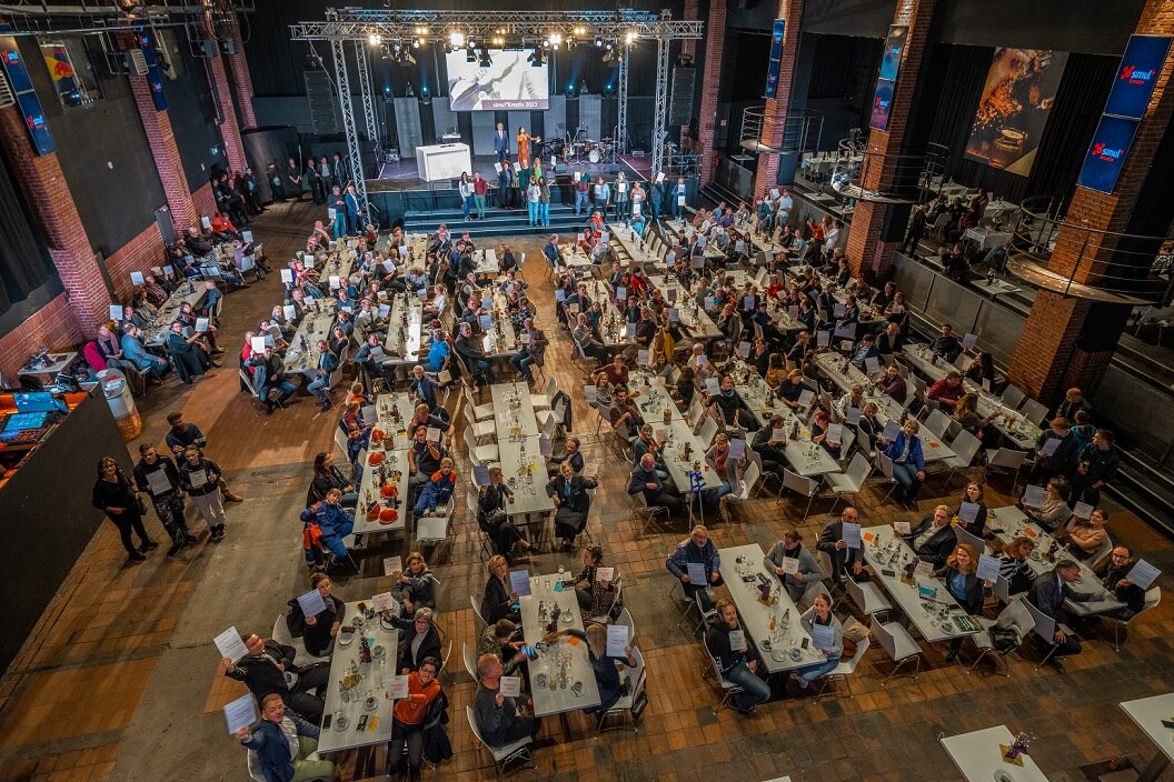 Blick in den Saal von oben mit vielen Tischen und Menschen