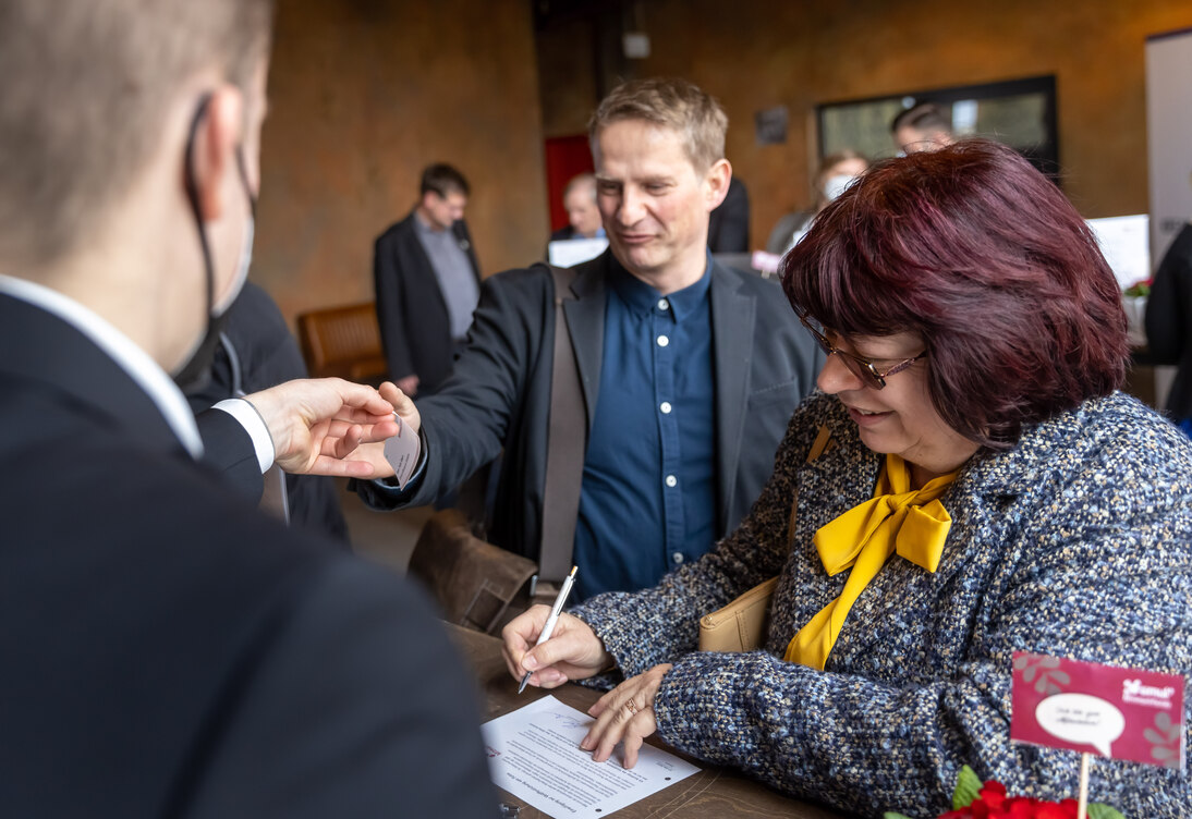 Eine Frau und ein Mann registrieren sich für die Veranstaltung an einem Tisch.