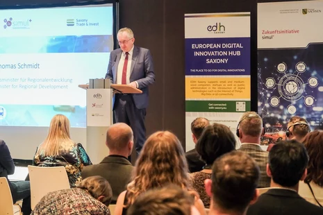 Staatsminister Schmidt steht auf dem Podium und hält eine Rede zum Publikum