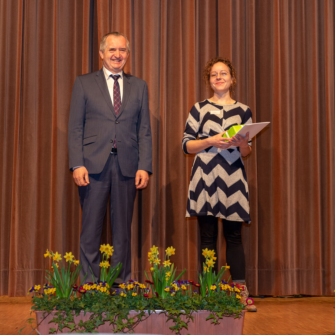Staatsminister Schmidt auf der Bühne mit einer Preisträgerin.